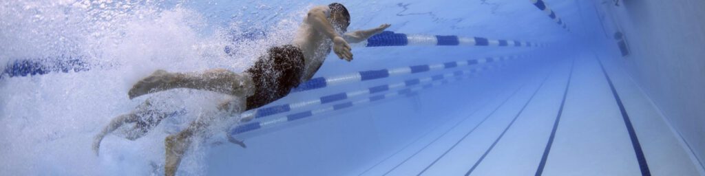 Startseite Das Bild zeit einen Schwimmer beim Kraulen im Wasser.